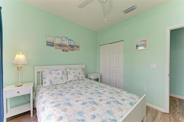 bedroom with visible vents, baseboards, a closet, and wood finished floors