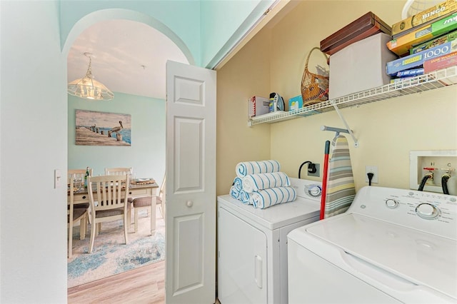 clothes washing area with separate washer and dryer, wood finished floors, and laundry area