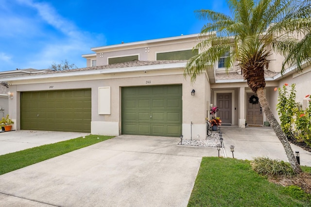 multi unit property with stucco siding, a garage, and driveway