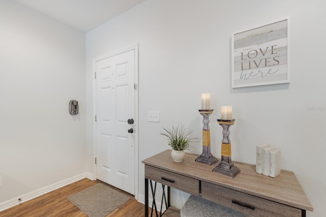 doorway to outside featuring baseboards and wood finished floors