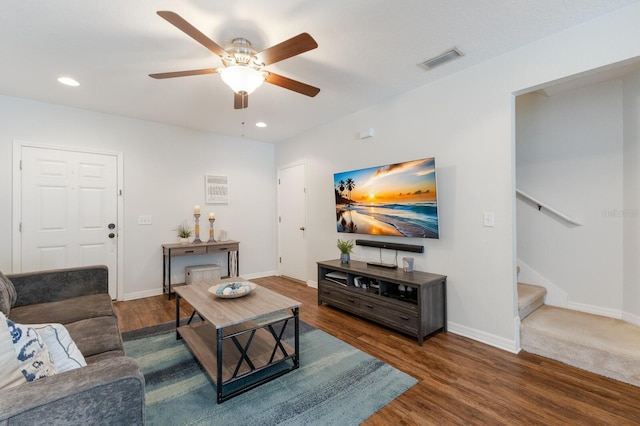 living room with wood finished floors, baseboards, visible vents, ceiling fan, and stairs