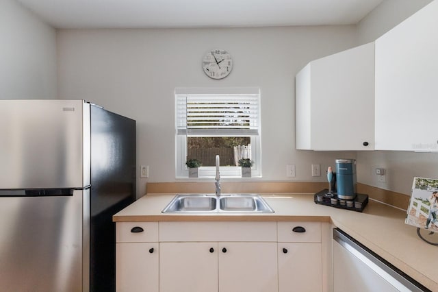 kitchen with a sink, dishwasher, light countertops, and freestanding refrigerator