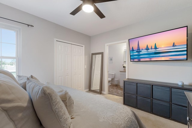 bedroom with a ceiling fan, ensuite bath, a closet, baseboards, and light colored carpet