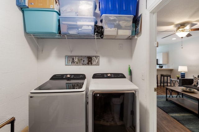 clothes washing area with washing machine and clothes dryer, laundry area, ceiling fan, and wood finished floors