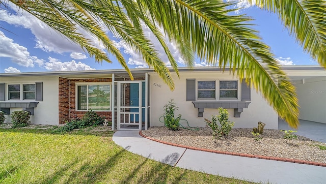 22201 Olean Blvd, Port Charlotte, FL 33952 - view of front of home with stucco siding, a front yard, and brick siding