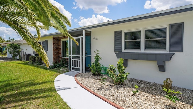 22201 Olean Blvd, Port Charlotte, FL 33952 - property entrance with stucco siding and a yard