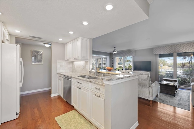 kitchen featuring a sink, open floor plan, a peninsula, freestanding refrigerator, and stainless steel dishwasher