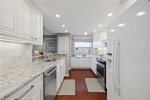 kitchen featuring light stone counters, dark wood finished floors, a sink, stainless steel appliances, and white cabinetry