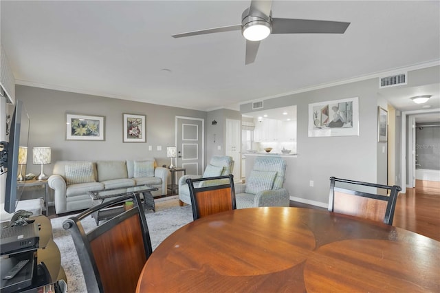 dining space with visible vents, ceiling fan, baseboards, ornamental molding, and wood finished floors