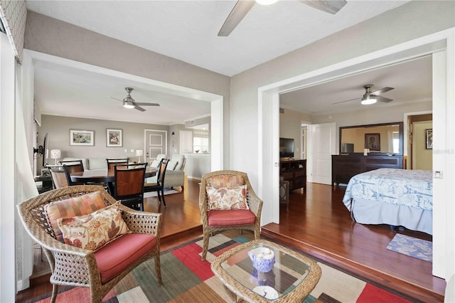 living room with wood finished floors, a ceiling fan, and ornamental molding