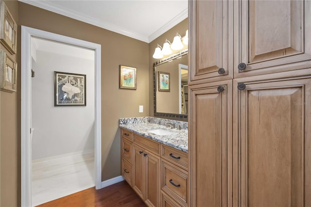 bathroom with vanity, wood finished floors, baseboards, and ornamental molding