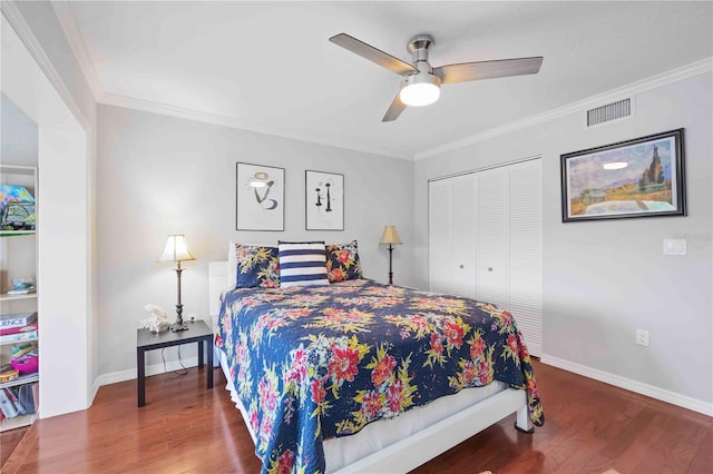 bedroom featuring a closet, visible vents, ornamental molding, and wood finished floors