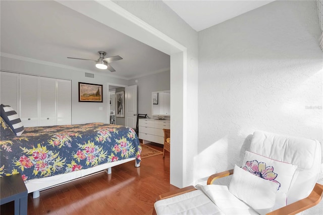 bedroom with visible vents, wood finished floors, a closet, crown molding, and ceiling fan