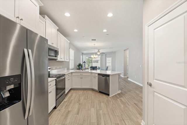 5998 Amberly Dr, Bradenton, FL 34208 - kitchen with recessed lighting, stainless steel appliances, a peninsula, white cabinets, and light countertops