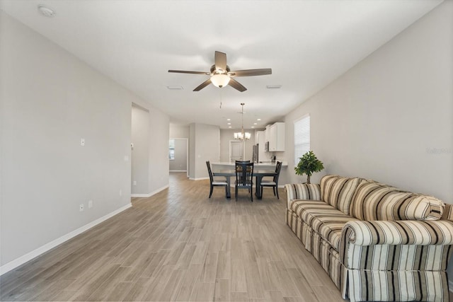 5998 Amberly Dr, Bradenton, FL 34208 - living room with ceiling fan with notable chandelier, light wood-type flooring, and baseboards