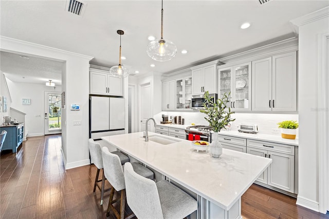 kitchen featuring visible vents, a sink, a breakfast bar area, appliances with stainless steel finishes, and a kitchen island with sink