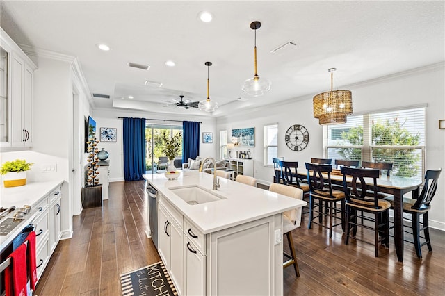 kitchen featuring stainless steel appliances, a sink, dark wood-type flooring, a kitchen bar, and crown molding