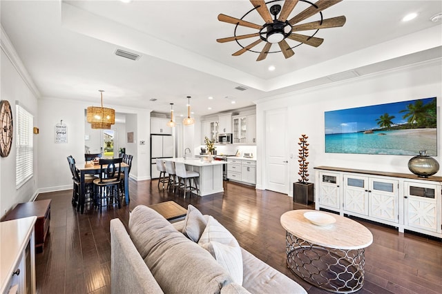 living area featuring a tray ceiling, baseboards, ceiling fan, and dark wood-style flooring