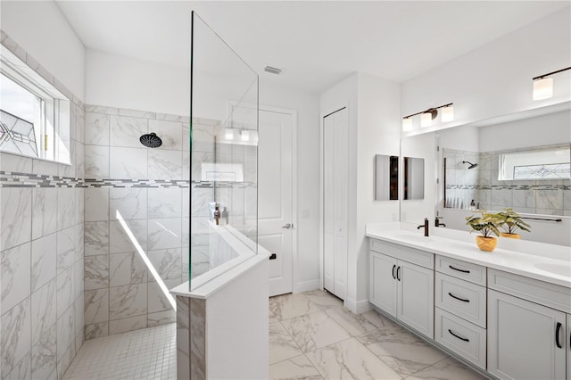 bathroom with a sink, marble finish floor, a walk in shower, and double vanity