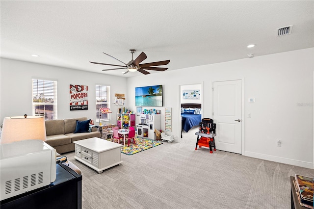 rec room with a textured ceiling, a ceiling fan, visible vents, and light carpet