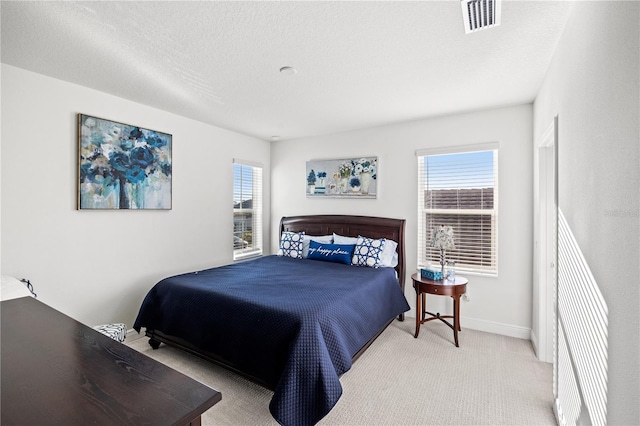 bedroom featuring visible vents, multiple windows, a textured ceiling, and carpet