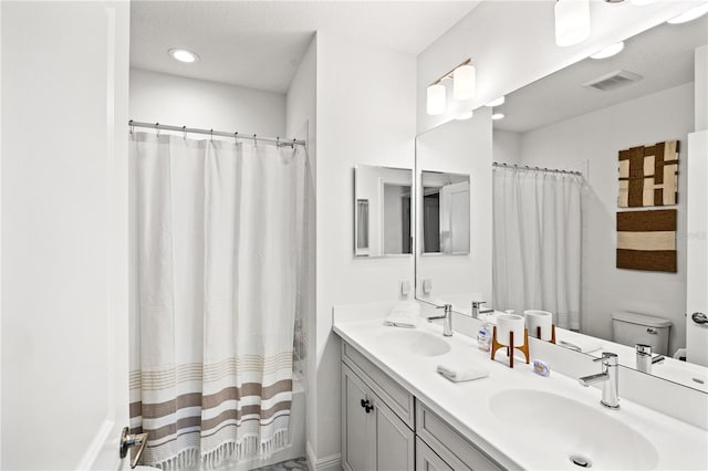 full bathroom with double vanity, visible vents, toilet, and a sink