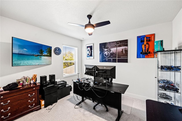 carpeted home office featuring baseboards, a textured ceiling, and ceiling fan