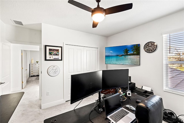 carpeted home office featuring visible vents, baseboards, a textured ceiling, and ceiling fan