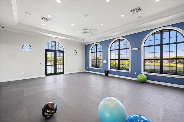 exercise area with visible vents, baseboards, a raised ceiling, and a ceiling fan