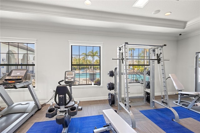 exercise room featuring a raised ceiling, recessed lighting, baseboards, and ornamental molding