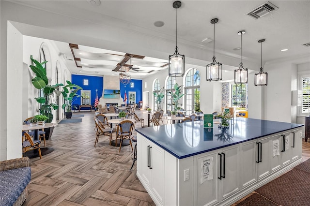 kitchen with visible vents, a kitchen island, dark countertops, open floor plan, and white cabinetry