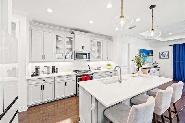 kitchen with a sink, stainless steel appliances, a breakfast bar, recessed lighting, and dark wood-style flooring