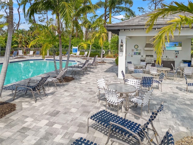 pool featuring fence, area for grilling, an outdoor kitchen, and a patio area