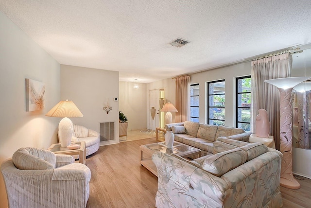 living area featuring visible vents, a textured ceiling, and light wood finished floors