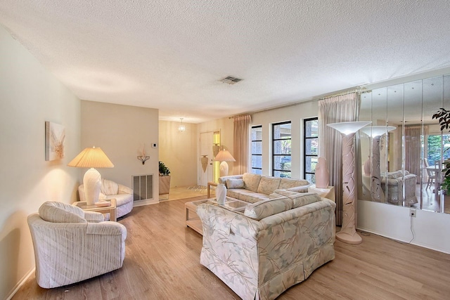 living room featuring visible vents, a healthy amount of sunlight, and light wood-style flooring