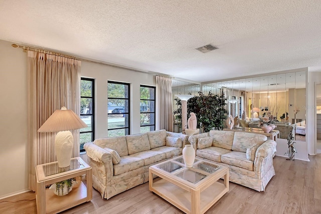 living area featuring light wood-style flooring, visible vents, and a textured ceiling