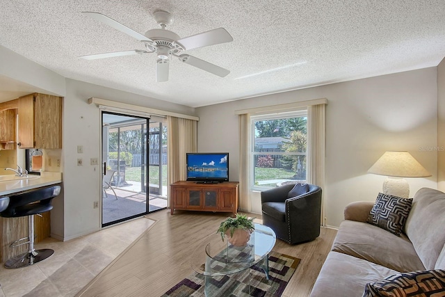 living area featuring a ceiling fan, light wood-style floors, and a wealth of natural light