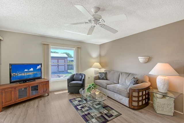 living room featuring light wood-type flooring, a textured ceiling, and a ceiling fan