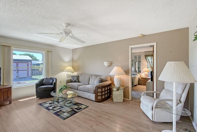 living room with ceiling fan, a textured ceiling, and wood finished floors