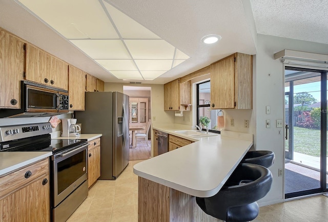 kitchen with light countertops, a kitchen breakfast bar, appliances with stainless steel finishes, and a sink