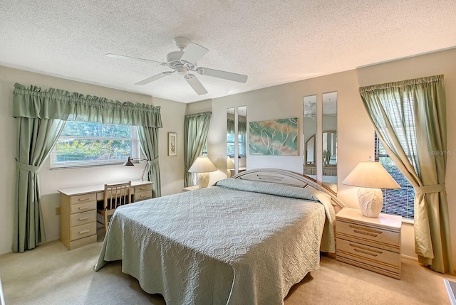 bedroom with a textured ceiling, light colored carpet, and ceiling fan