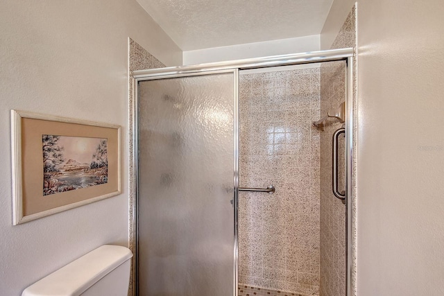 bathroom with a shower stall, toilet, and a textured ceiling