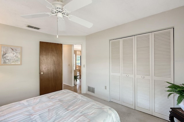 bedroom featuring a ceiling fan, light colored carpet, visible vents, and a closet