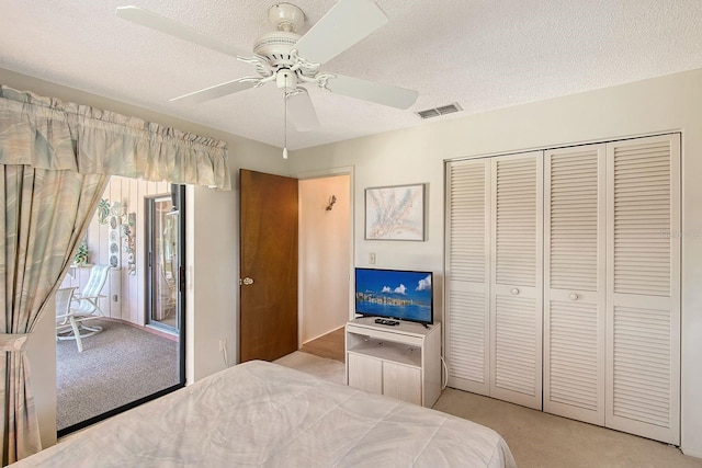 bedroom featuring a textured ceiling, visible vents, a closet, and light carpet