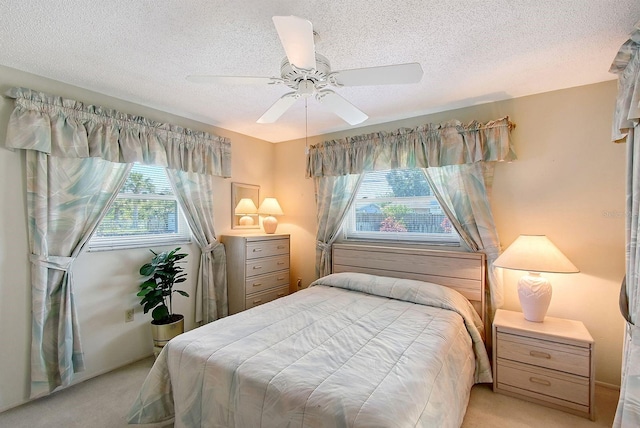 bedroom featuring light carpet, a textured ceiling, and a ceiling fan