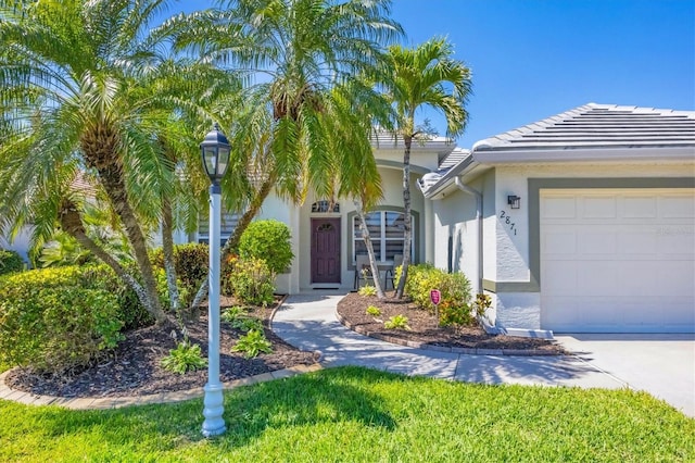 view of front of house with stucco siding, a garage, and a tiled roof