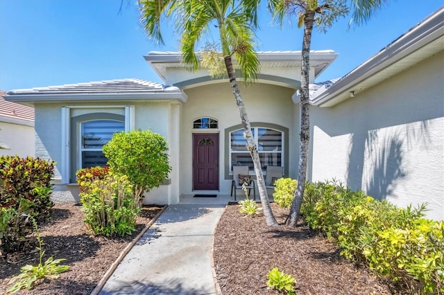 entrance to property with stucco siding and a tile roof