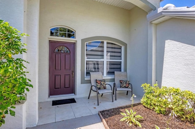 view of exterior entry featuring stucco siding and a porch