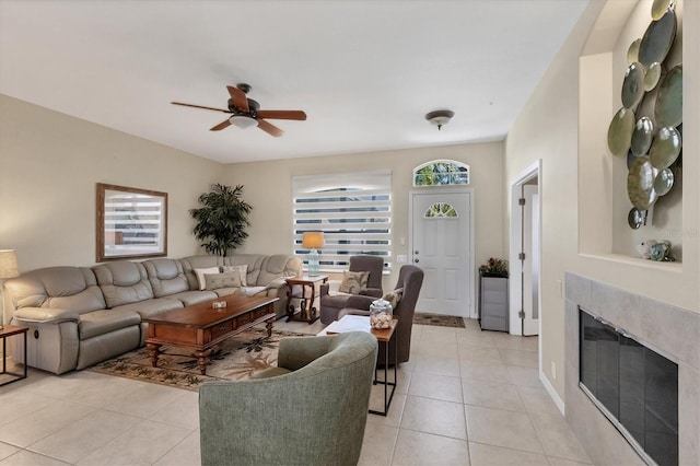 living area featuring light tile patterned floors, a glass covered fireplace, and ceiling fan