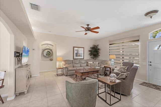 living area featuring light tile patterned floors, arched walkways, visible vents, and ceiling fan